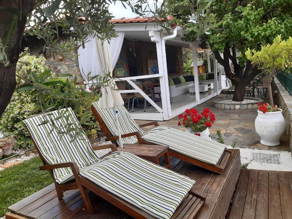 un grupo de sillas sentadas en una terraza de madera en Nikos Stone House 80m from the beach with wifi, en Gerakini