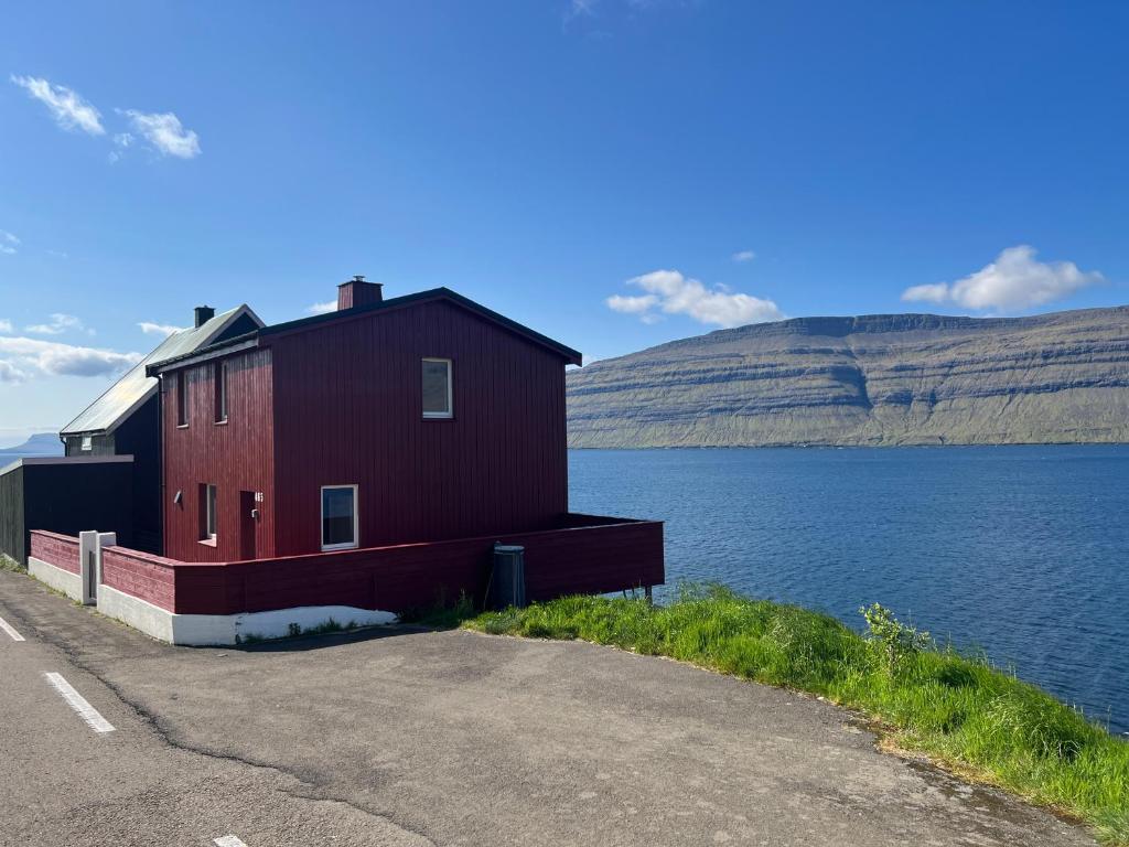 ein rotes Gebäude an der Seite eines Wasserkörpers in der Unterkunft The Cozy red house with Amazing sea view 