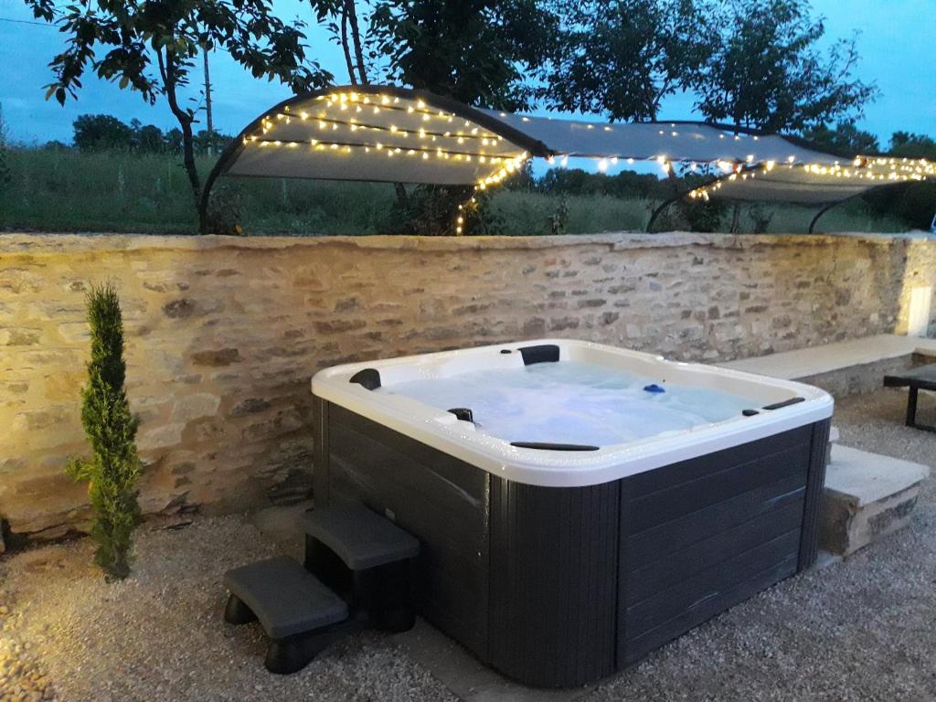 a hot tub sitting next to a stone wall at Bergerie du Causse in Livernon