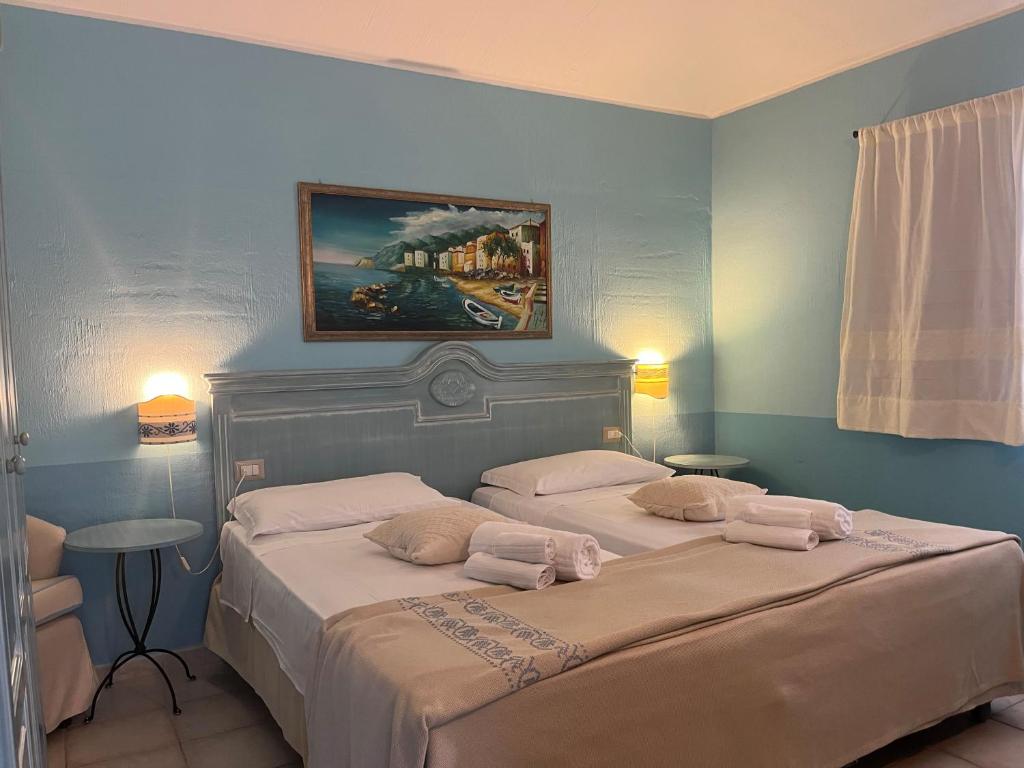 a bedroom with two beds and a painting on the wall at Hotel Baia Cea in Bari Sardo