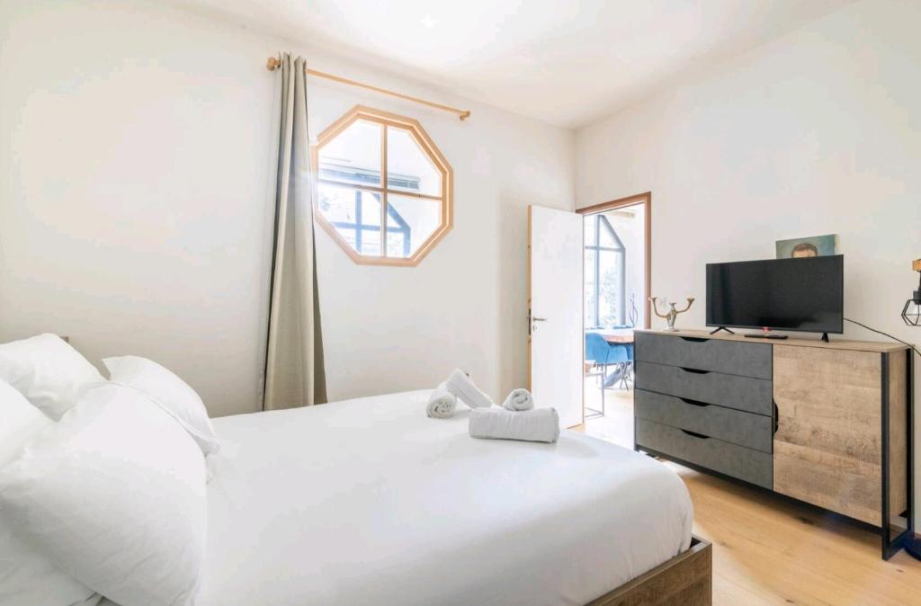 a bedroom with a white bed and a tv at Appartement luxe "La providence" , plein centre in Vichy