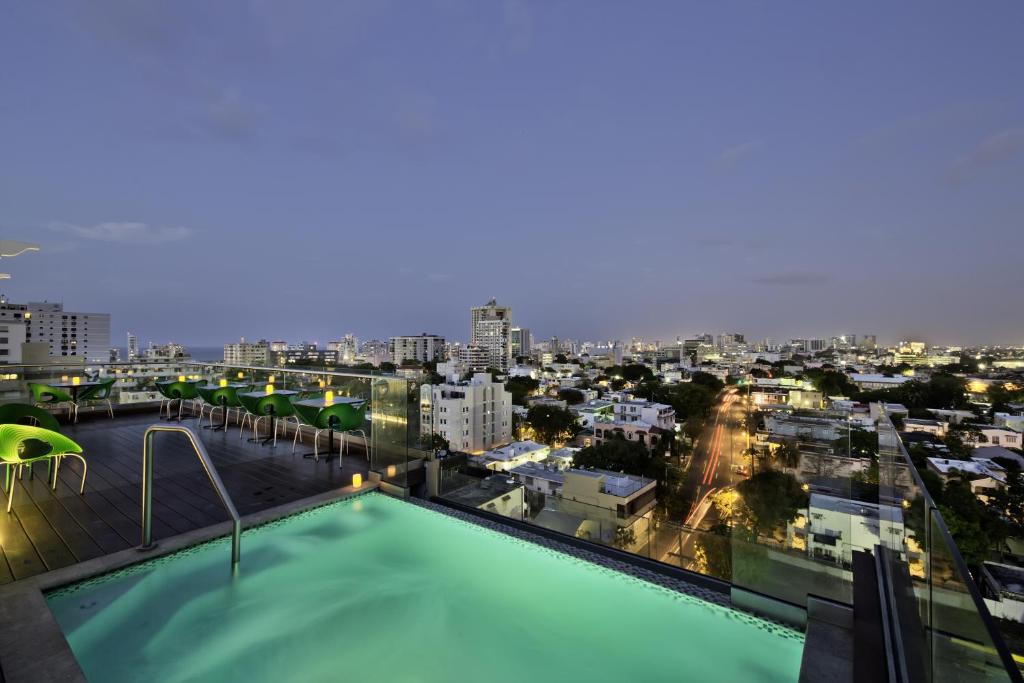 a swimming pool on the roof of a building with a city at Ciqala Luxury Suites - San Juan in San Juan