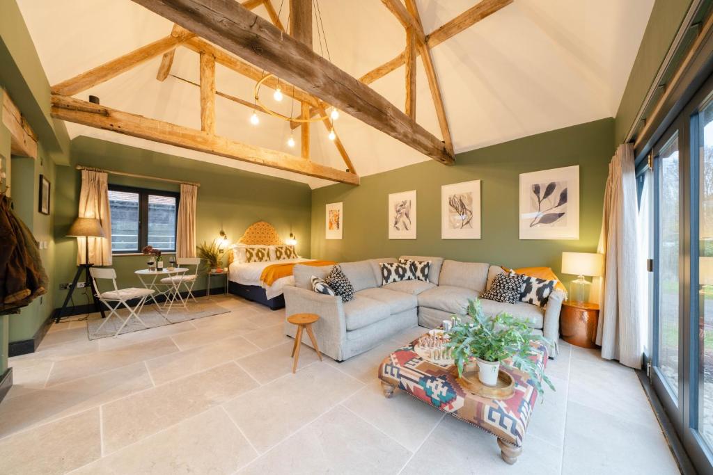 uma sala de estar com um sofá e uma cama em Spinney - a unique open plan barn, with private garden em Evesham