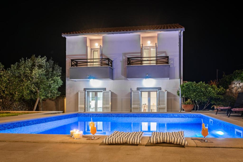 a building with a swimming pool in front of a house at Villa Mediterana in Vis