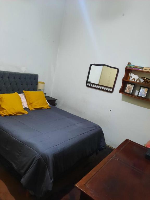 Un dormitorio con una cama con almohadas amarillas y una mesa. en Kela en Buenos Aires