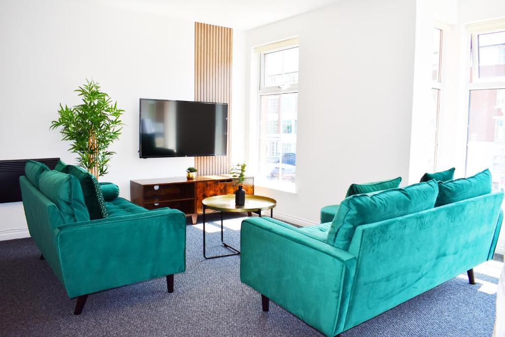 a living room with two blue couches and a tv at City Center Apartments FREE PARKING in Liverpool