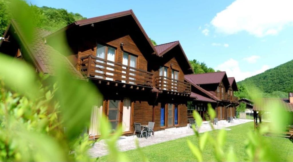 a wooden house with a green mountain in the background at Relax and Smile Rameț in Biceşti
