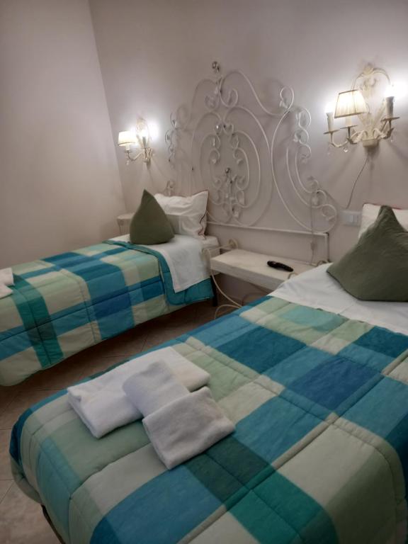 um quarto com 2 camas e toalhas em Mini alloggio rosmarino vicino alla porta Elisa em Lucca