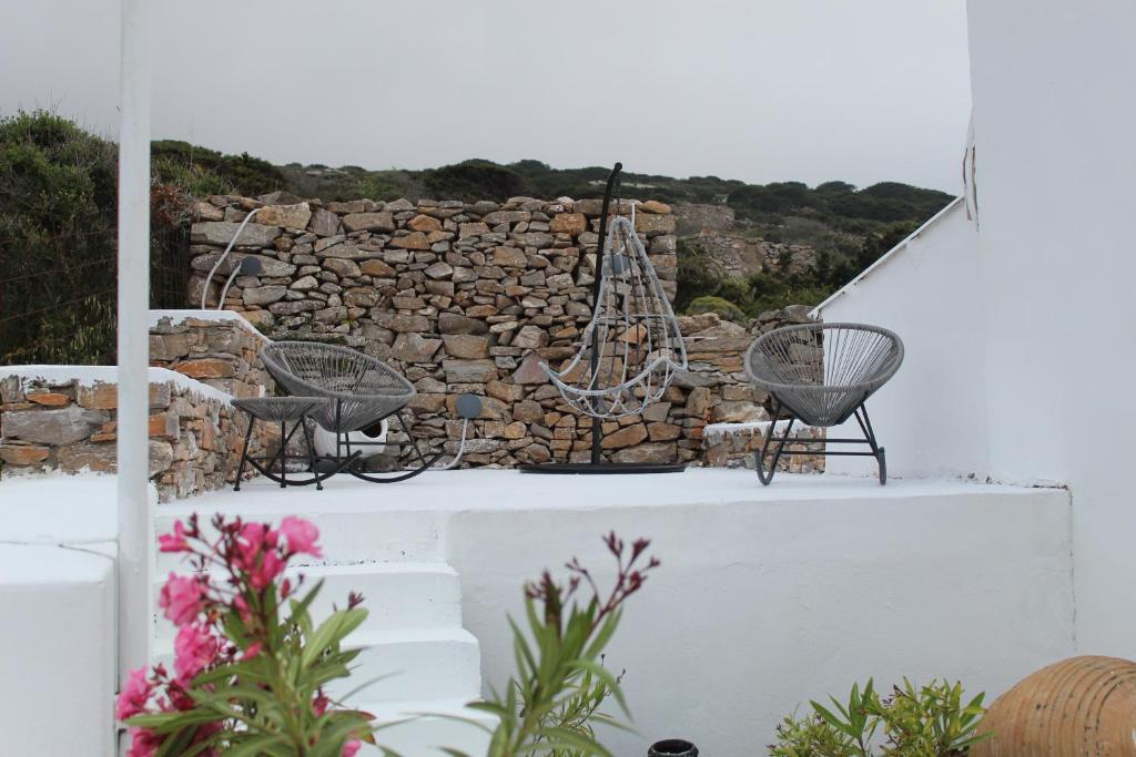two chairs sitting on a ledge next to a stone wall at Cycladic Villa in Amorgos Island (Maison Shiro) in Arkesíni