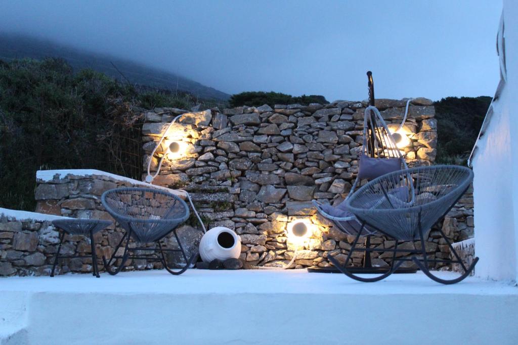 a stone wall with two chairs and lights at Cycladic Villa in Amorgos Island (Maison Shiro) in Arkesíni