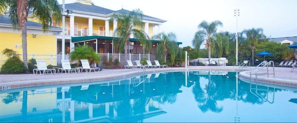 una piscina frente a una casa con palmeras en Bahama Bay Resort & Spa - Deluxe Condo Apartments, en Kissimmee