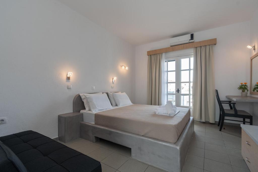 a bedroom with a bed and a desk and a window at Astri Hotel in Neos Marmaras