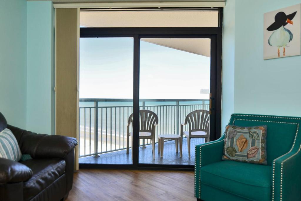 a living room with a couch and a chair and a balcony at Paradise Ocean View at Top Resort w Lazy River in Myrtle Beach