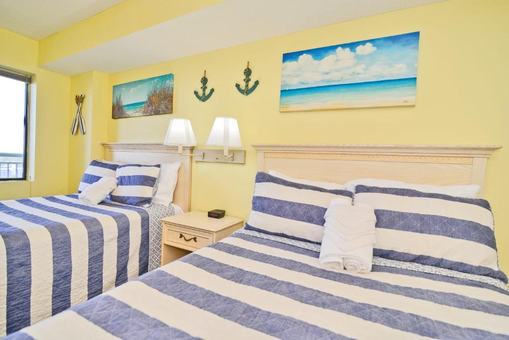 two beds in a room with yellow walls at Paradise Ocean View at Top Resort w Lazy River in Myrtle Beach