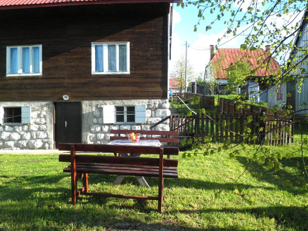 a bench in the grass in front of a building at Central Rustic House in Žabljak