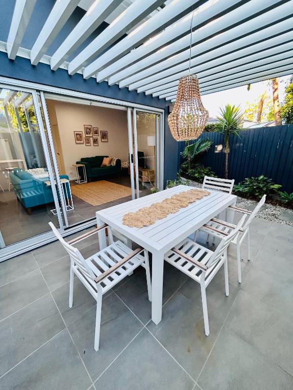 a white table and chairs on a patio with a chandelier at Location, location, location - ground floor in Brisbane