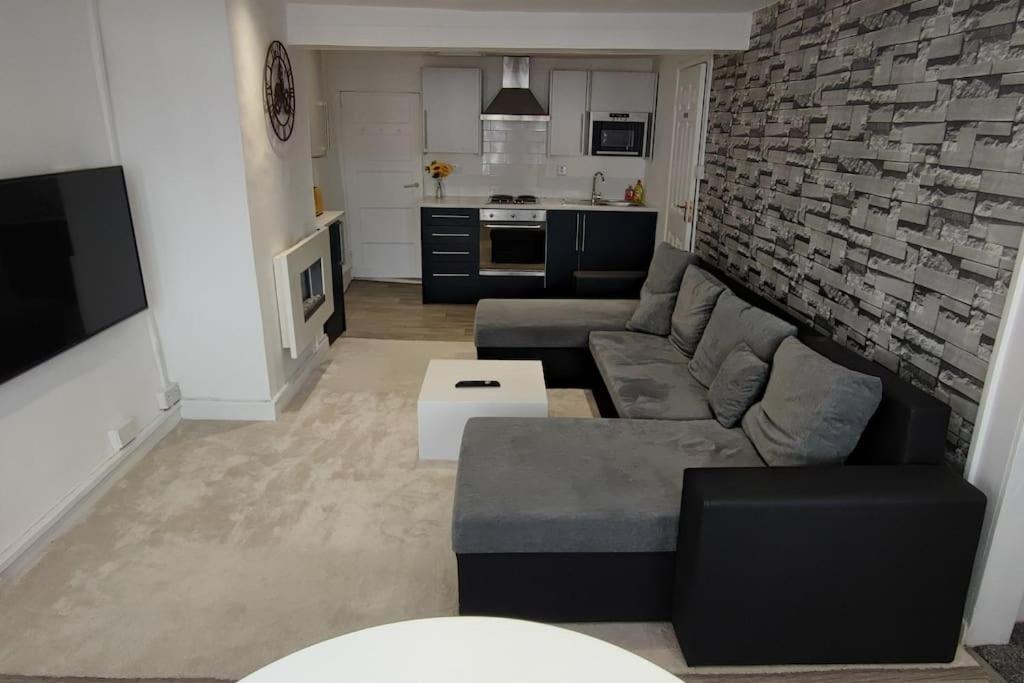 Cosy 1 Bedroom Flat in Southam في ساوثهام: غرفة معيشة مع أريكة وجدار من الطوب
