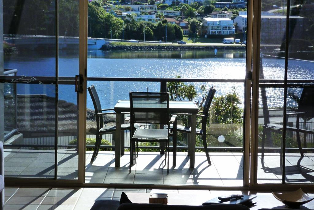 Sails Luxury Apartments Merimbula في ميريمبولا: طاولة وكراسي على شرفة مطلة على الماء