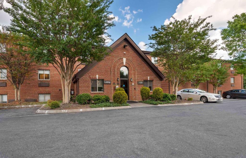 a brick building with a car parked in a parking lot at Extended Stay America Select Suites - Charlotte - University Place - E McCullough Dr in Charlotte