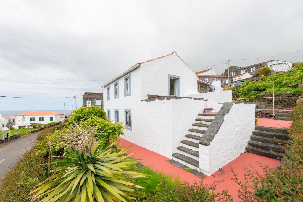 a white house with stairs on the side of a street at Lobo do Mar in Calheta de Nesquim