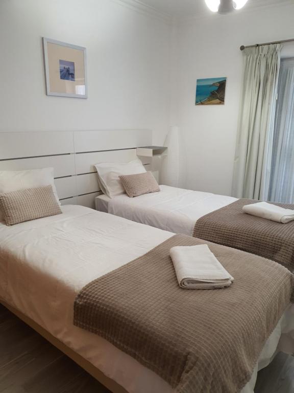 2 łóżka w pokoju hotelowym z ręcznikami w obiekcie Apartamento Sol e Mar Sesimbra w mieście Sesimbra