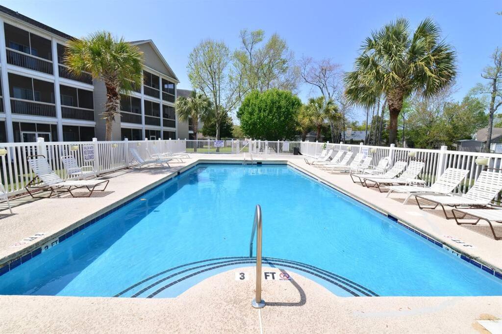ein Swimmingpool mit Liegestühlen und ein Gebäude in der Unterkunft All New Luxury Beach Retreat 1 Mile to Beach w Pool in Myrtle Beach
