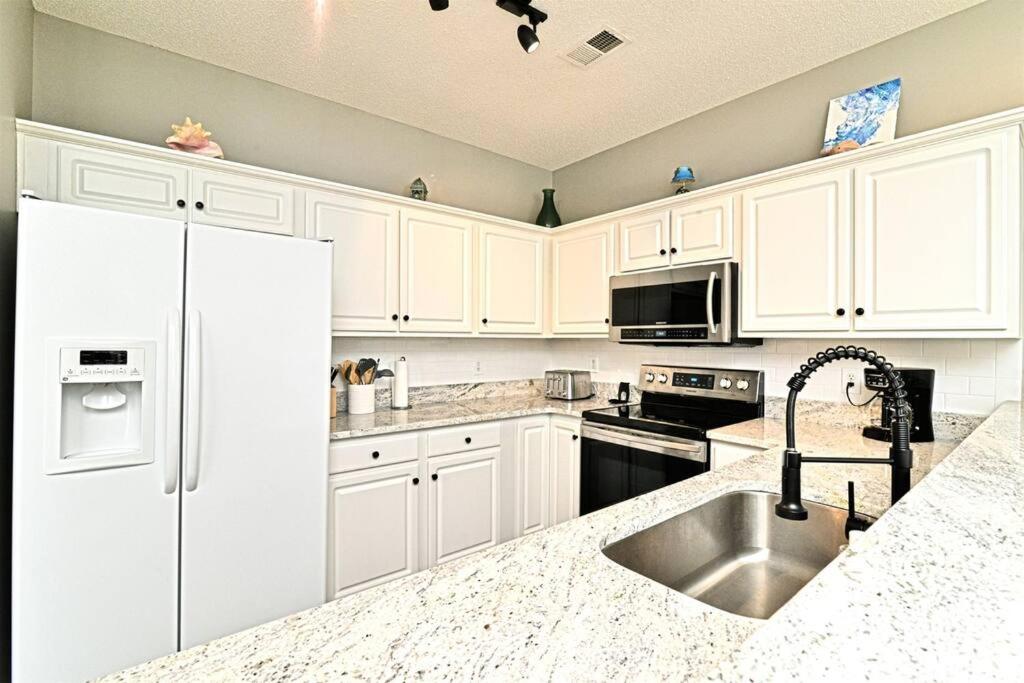 eine Küche mit weißen Schränken und einer Spüle in der Unterkunft All New Luxury Beach Retreat 1 Mile to Beach w Pool in Myrtle Beach