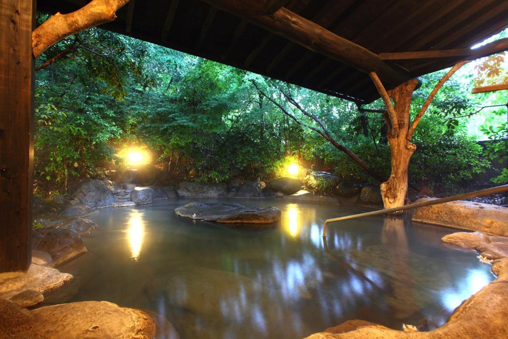 un bassin d'eau avec des arbres et des lumières dans l'établissement Yamashinobu, à Minamioguni