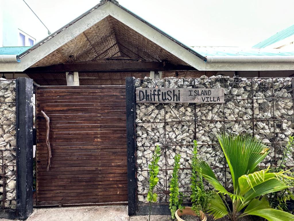 ein Schild an einer Wand neben einer Garage in der Unterkunft Dhiffushi Island Villa in Dhiffushi