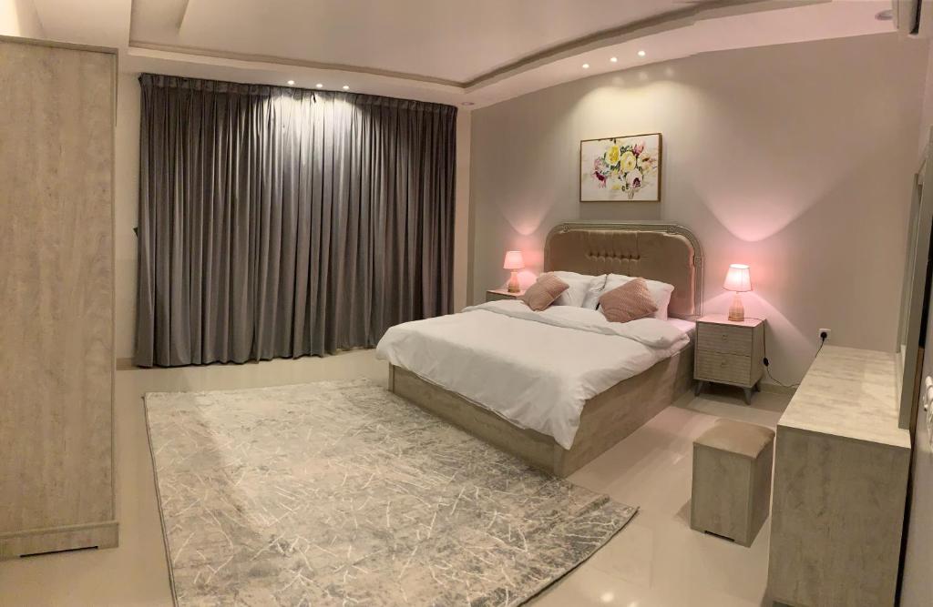 een slaapkamer met een bed met 2 lampen en een raam bij شقق العارض in Riyad