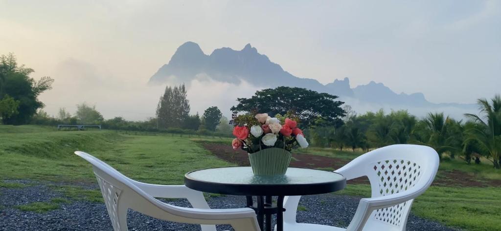 une table et des chaises avec un vase de fleurs. dans l'établissement ไร่วิวทิวเขา ลานกางเต็นท์ ฟาร์มสเตย์, à Ban Nong Tum