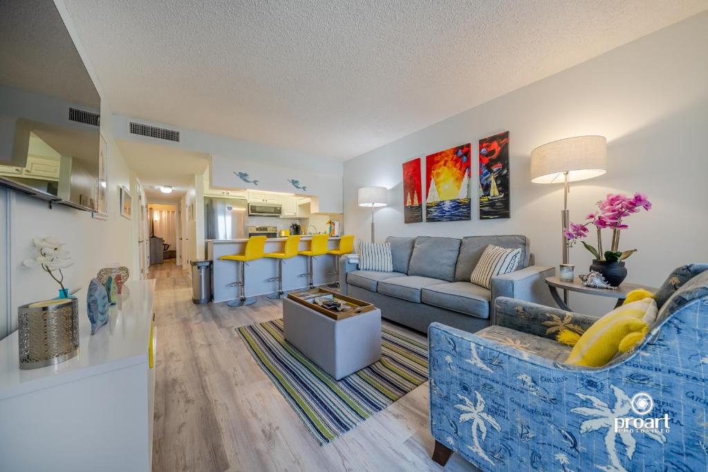 a living room with a blue couch and yellow chairs at Hello Sunshine Steps To the Beach in Destin