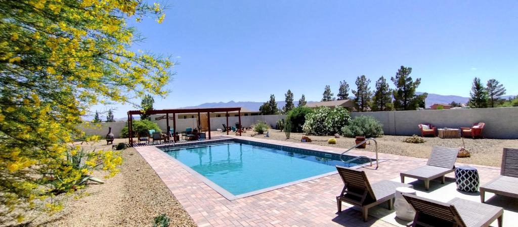 a swimming pool in a yard with chairs and a patio at Falcon Cottage in Pahrump
