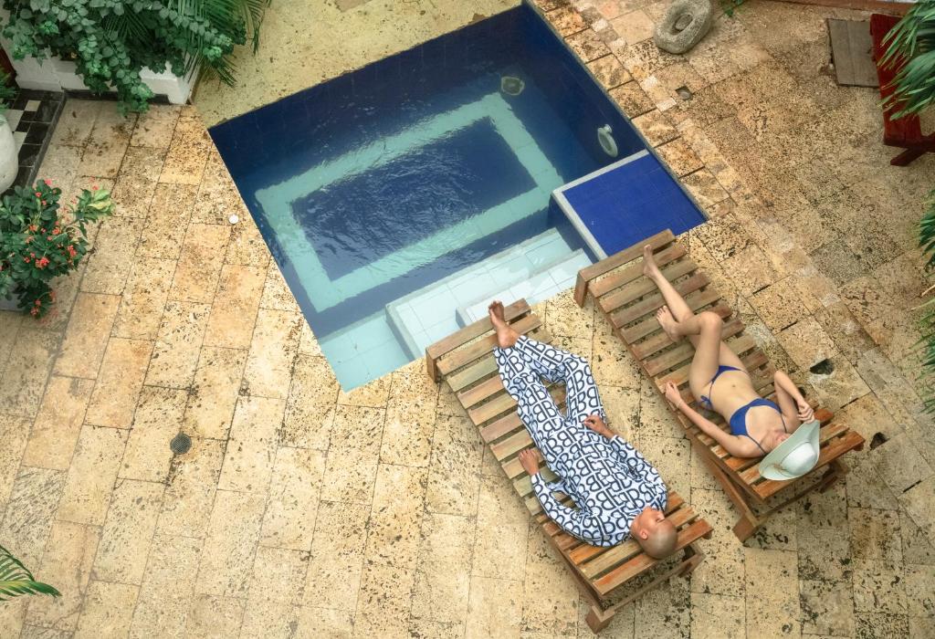 two people laying on deck chairs next to a swimming pool at La Puerta Azul in Santa Marta