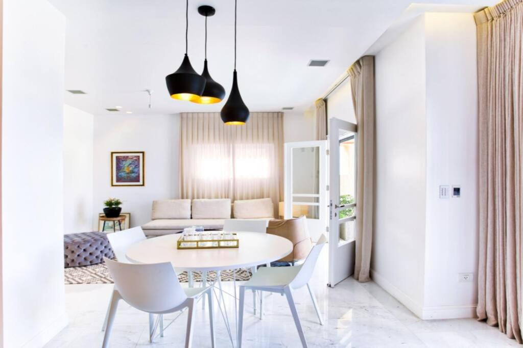 a dining room and living room with a white table and chairs at New renovated APT, HaYarkon in front of the beach in Tel Aviv