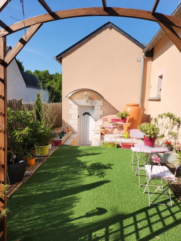 a garden with artificial grass and chairs in front of a house at les oliviers in Veigné