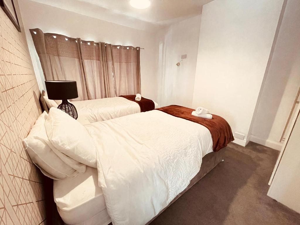 Charming 3-Bed holiday House in Birmingham في برمنغهام: غرفة نوم بسريرين مع شراشف بيضاء