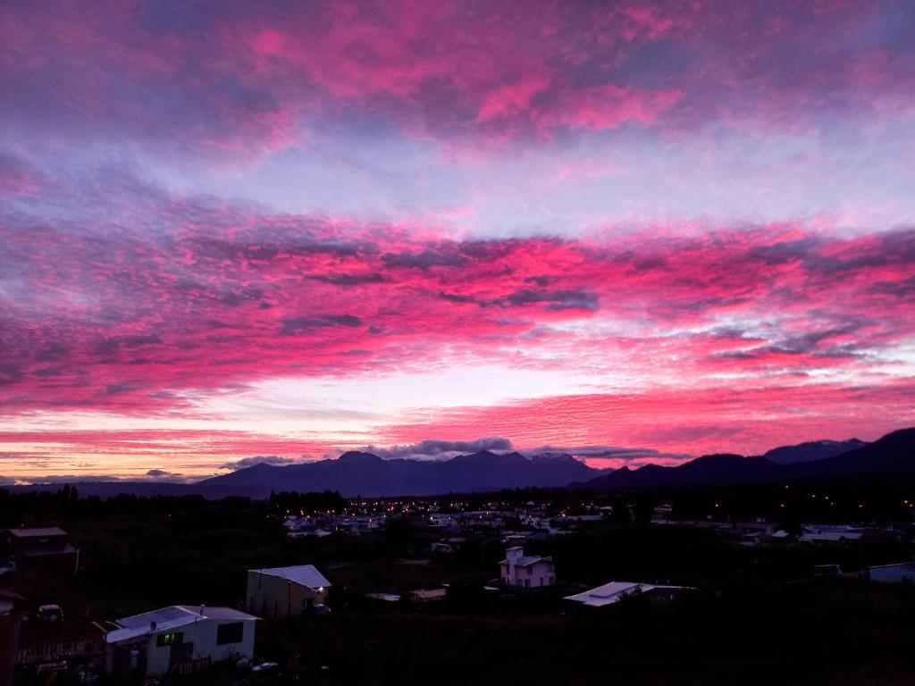 una puesta de sol con nubes rojas en el cielo en Hostel Luan Posada de Montaña en Trevelín