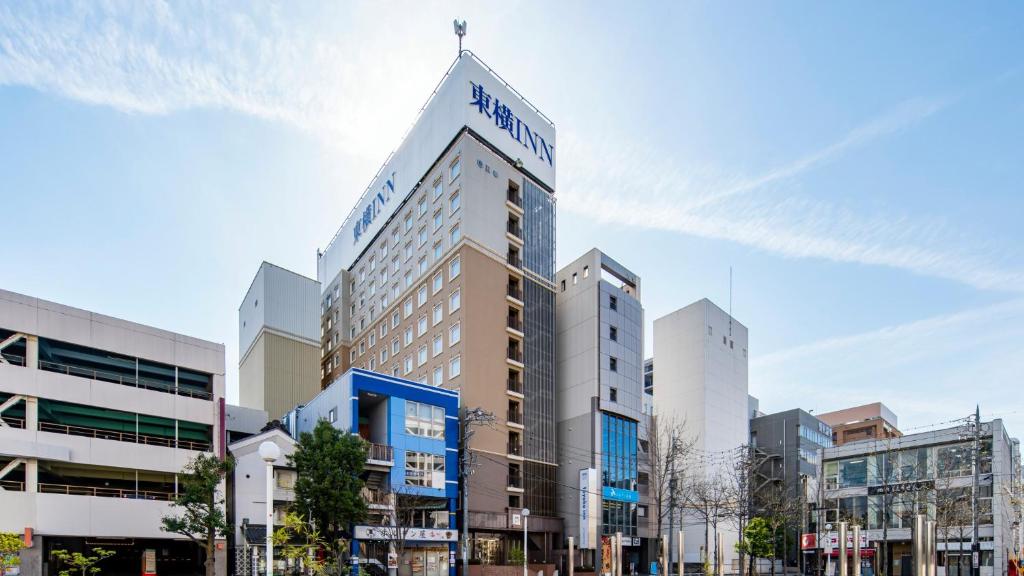 a tall building with a sign on top of it at Toyoko Inn Matsumoto Ekimae Hommachi in Matsumoto