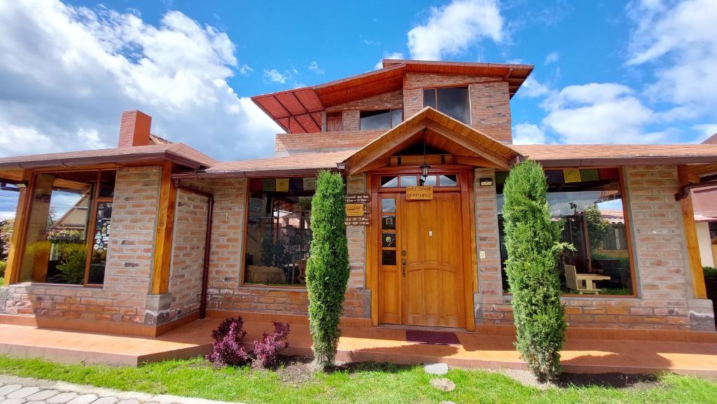 een stenen huis met een houten deur en ramen bij Casa del Montañero in Machachi