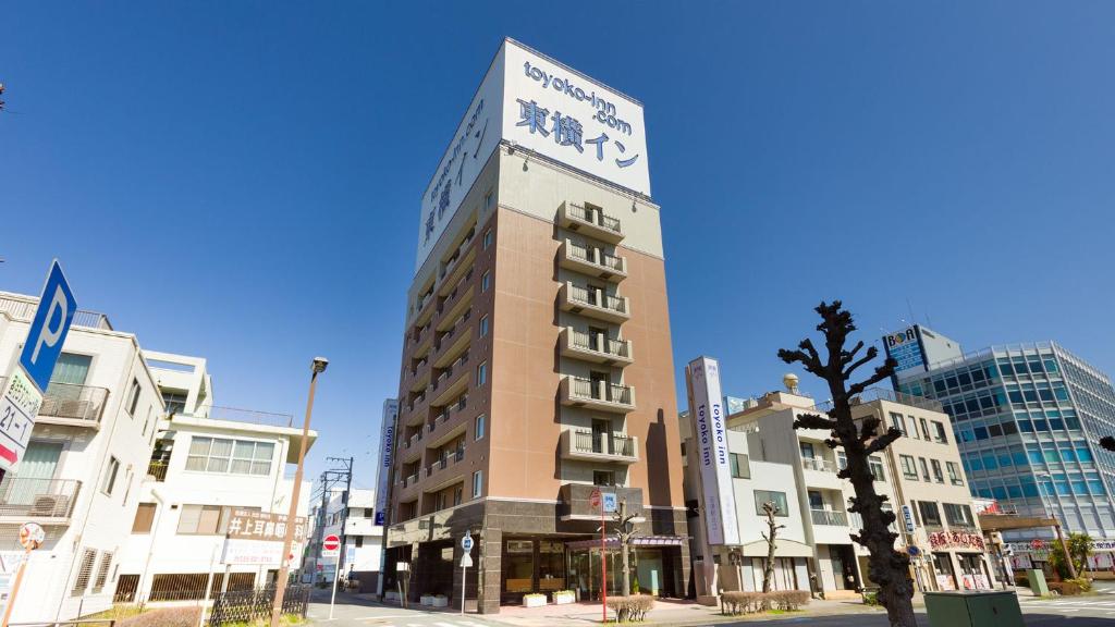 a tall building on a city street with buildings at Toyoko Inn Fujisan Numazu eki Kita guchi No 1 in Numazu