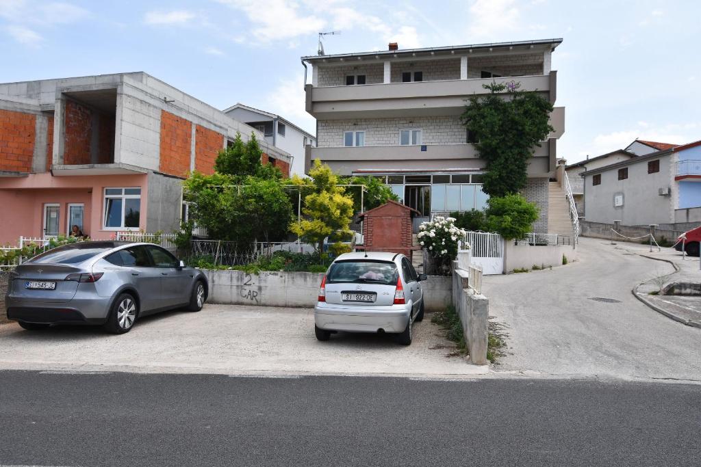two cars parked in a parking lot next to a building at Apartments Zorana in Rogoznica