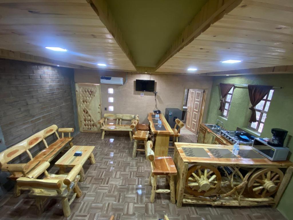 Habitación con mesas y sillas de madera y TV. en Cabañas Rochivo Ranch en Creel