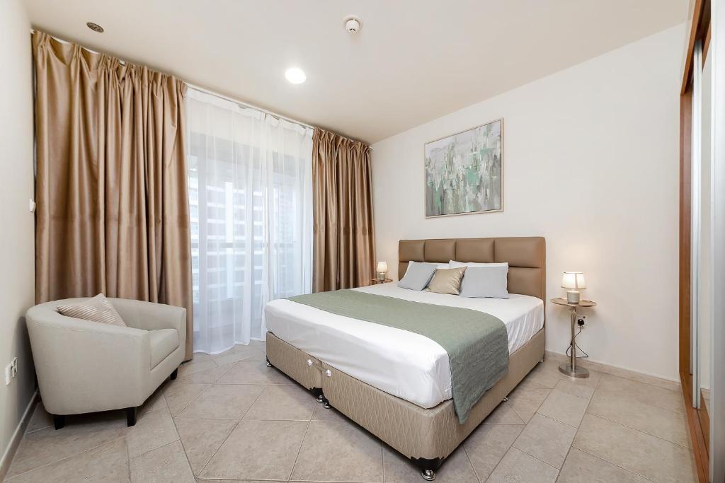 a bedroom with a bed and a chair and a window at Luxury Princess Tower 1 Br Brand New Furnished apartment in Dubai