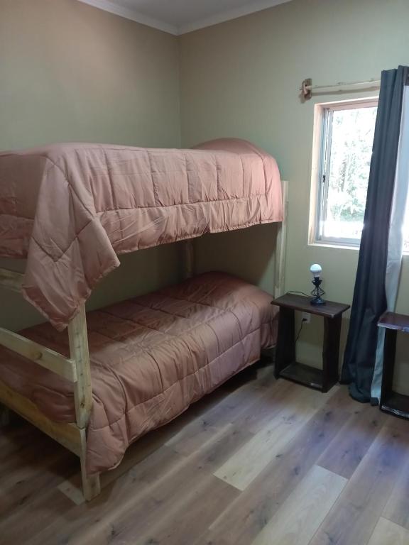 a bedroom with two bunk beds and a window at El roble cabañas hualle in Pucón