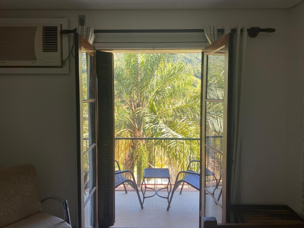 Habitación con puerta que da a un balcón con sillas. en Hotel Cavalinho Branco, en Águas de Lindóia