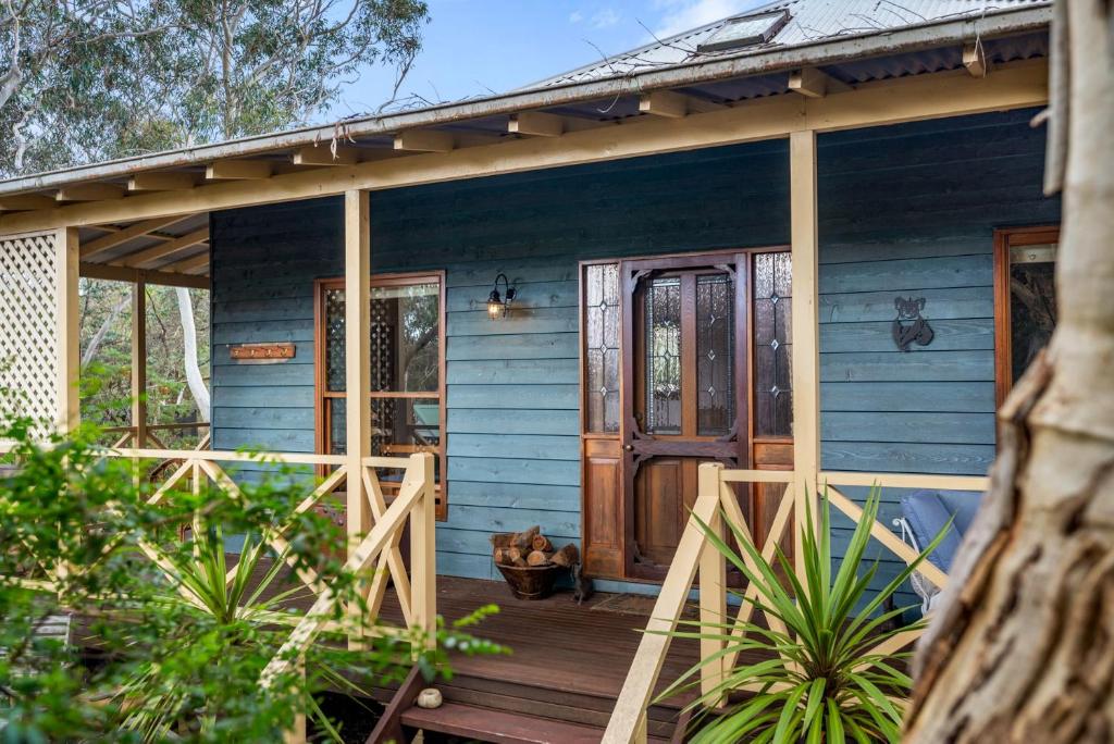 una casa azul con una puerta de madera en un porche en Scribbly Gum, en Leura