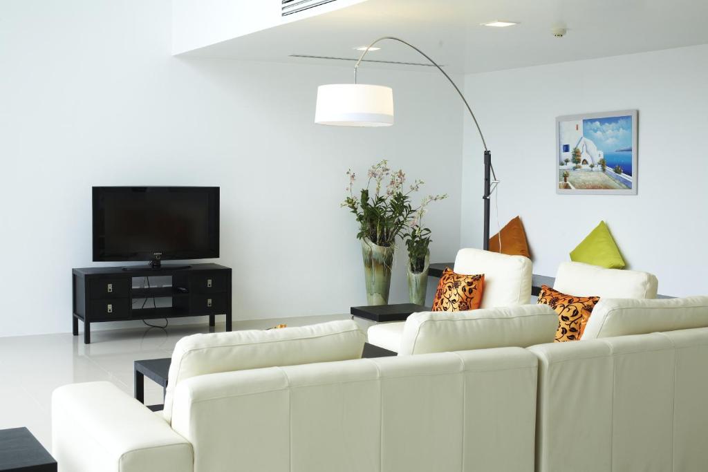 a living room with white furniture and a flat screen tv at Jirana Patong in Patong Beach