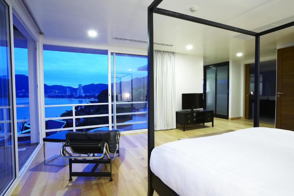 a bedroom with a bed and a balcony with a television at Jirana Patong in Patong Beach