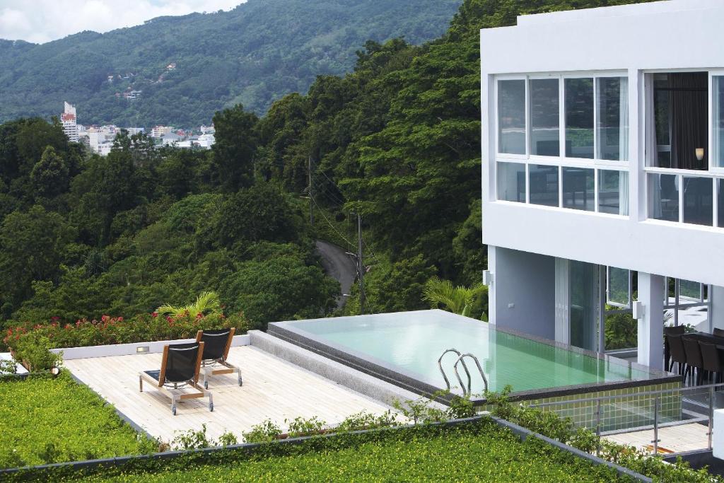 a house with a swimming pool and mountains in the background at Jirana Patong in Patong Beach